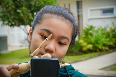 Portrait of boy holding mobile phone outdoors