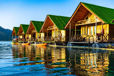 Buildings by lake against sky