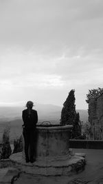 Rear view of man and woman standing by tree against sky