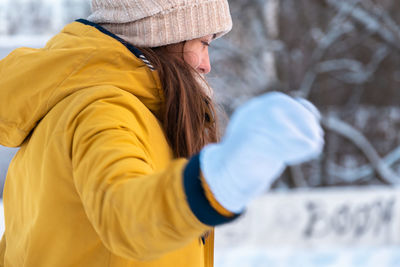 Portrait of happy young woman in yellow jacket skating at the rink