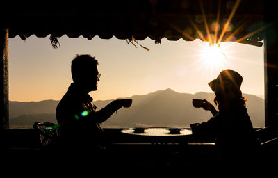 Couple sitting at restaurant against landscape