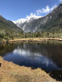 Scenic view of lake by mountains against sky