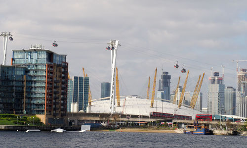 Bridge over river by buildings against sky