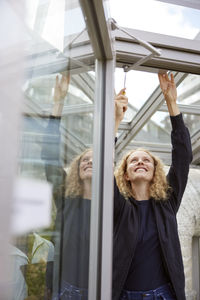 Portrait of young woman looking through window