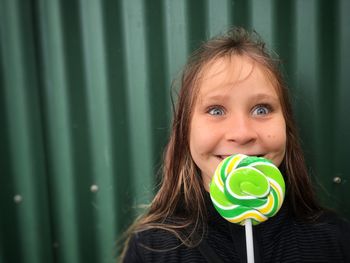 Close-up of smiling teenage girl holding green lollipop