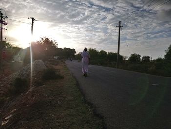 Rear view of man walking on street against sky