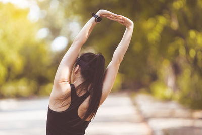 Midsection of woman with arms raised standing outdoors