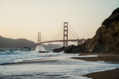 Suspension bridge over sea against clear sky
