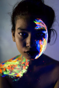 Close-up portrait of young woman with paint on face and shoulder