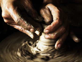 Cropped hands of man making pot in workshop