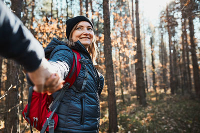 Couple holding hands enjoying trip while vacation day. hikers with backpacks walking on forest path