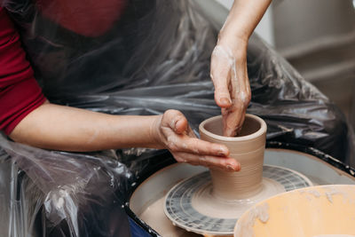 Close up of woman hands molding clay mug spinning on pottery wheel. potter hands forming clay cup