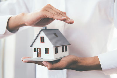 Midsection of man holding umbrella against house in building