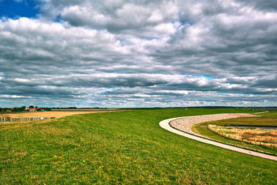 Scenic view of grassy field against cloudy sky