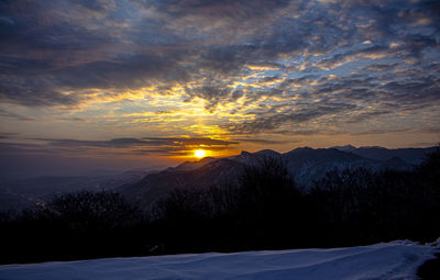 Scenic view of snowcapped mountains against sky at sunset