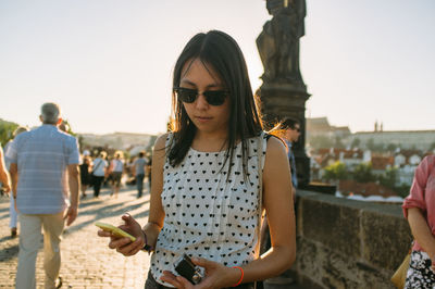 Woman using phone while standing in city
