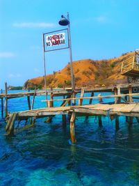 Information sign by sea against blue sky