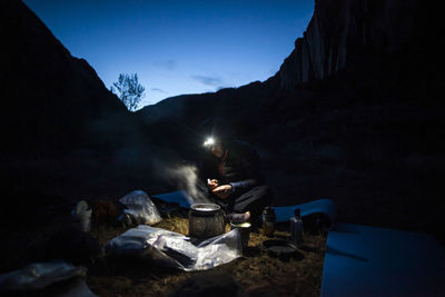 Woman cooks dinner by headlamp on escalante river, utah