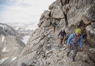 Three rock climbers hike along a cliff in the tetons of wyoming