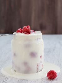 Close-up of raspberries with whipped cream in jar on table