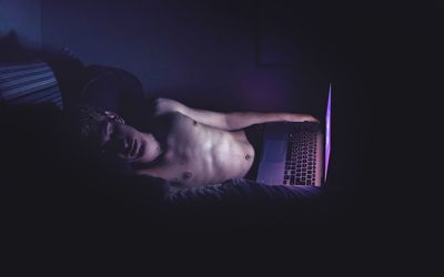 High angle view of man with laptop sleeping on bed at home