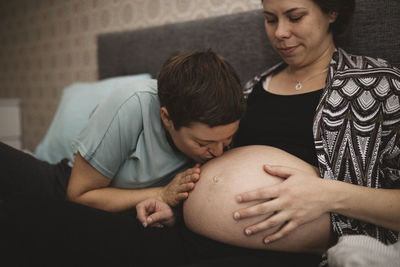Woman kissing pregnant girlfriend's belly