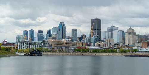 Modern buildings by river against sky in city