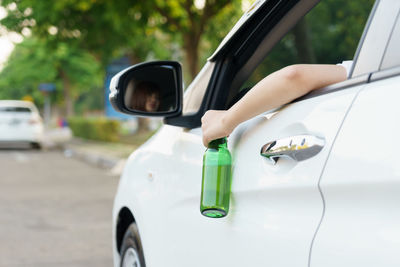 Woman holding beer bottle while driving car