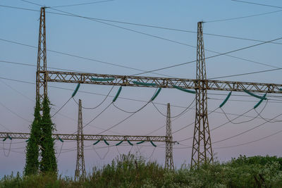 Low angle view of electricity pylon against clear blue sky