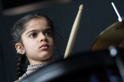 Girl wearing hearing aid while playing drum against wall