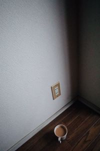 Empty coffee cup on table against wall at home