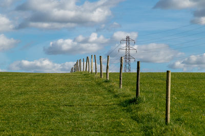 Electricity pylon on field against sky