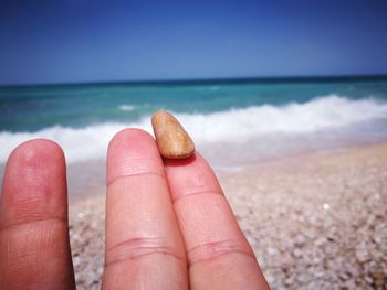 Close-up of hand against sea