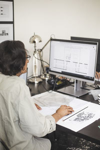 Senior female entrepreneur working on computer at table in office