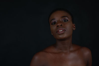 Portrait of shirtless young man against black background