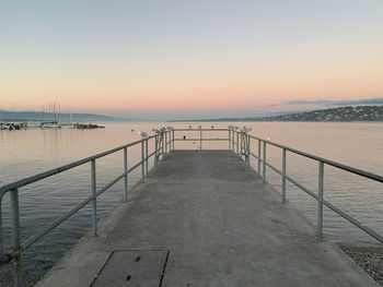 Pier over sea against clear sky during sunset