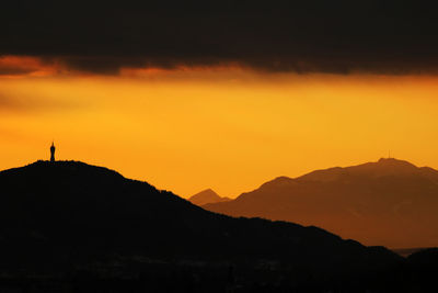 Silhouette mountains against orange sky