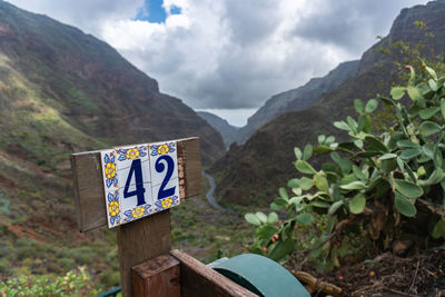 Information sign on mountain against sky