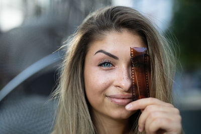 Close-up portrait of beautiful young woman with camera film