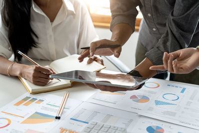 Midsection of business people working on table