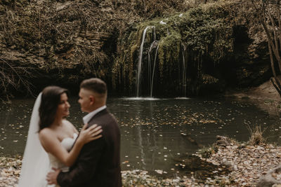 Rear view of woman standing against waterfall