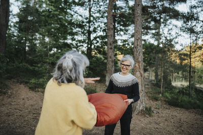 Two senior women setting up tent in forest