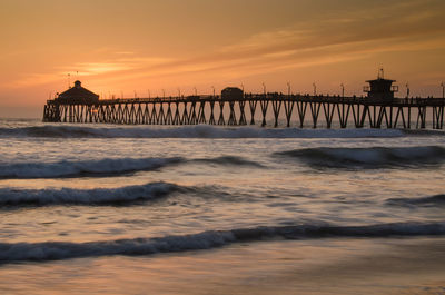 Silhouette pier over sea against sky during sunset