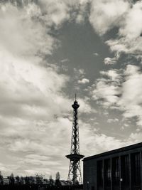 Low angle view of communications tower against cloudy sky
