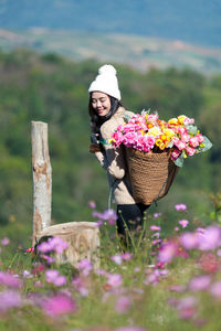 Smiling woman carrying flowers in basket