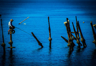 Wooden posts in sea against sky