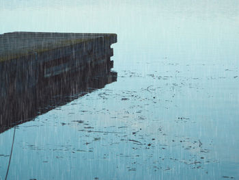 High angle view of wooden posts in sea against sky