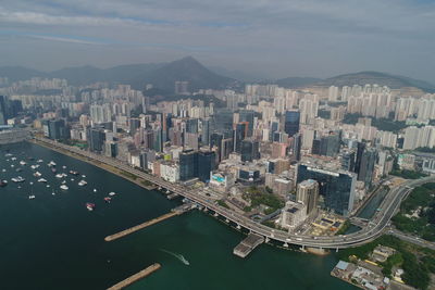 High angle view of city by river and buildings against sky