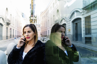 Young woman photographing through smart phone on street
