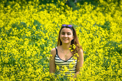 Portrait of smiling young woman amidst yellow flowering plants